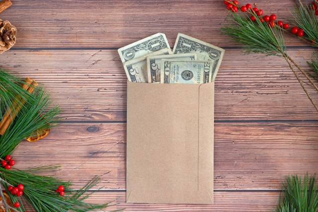 Paper envelope with cash inside surrounded by conifer trees - symbolizing gifts and earning money on Instagram.